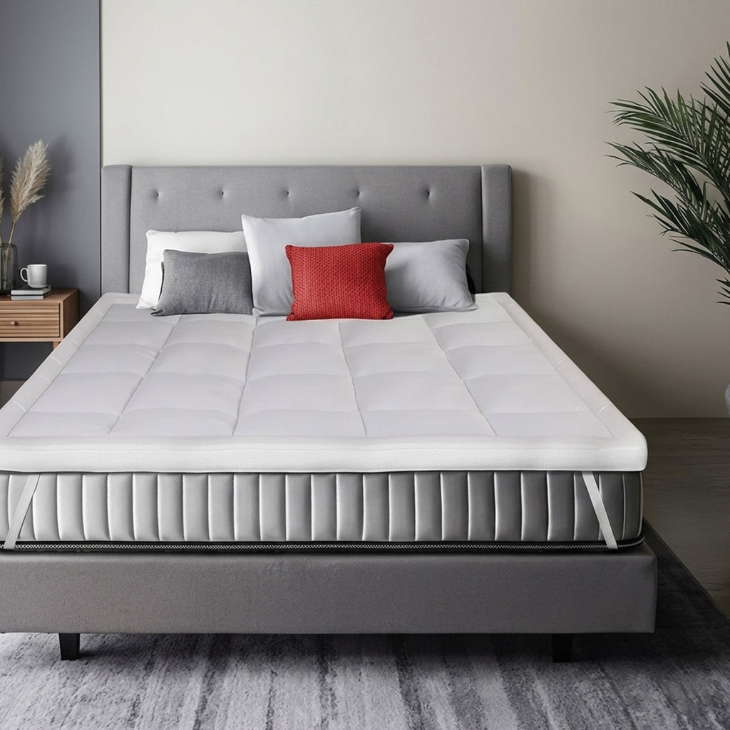 Gray bed with white mattress and red pillow in a bedroom setting