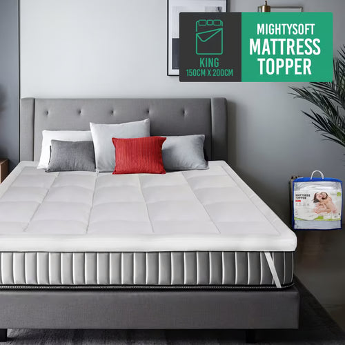 A white mattress topper on bed and pillows