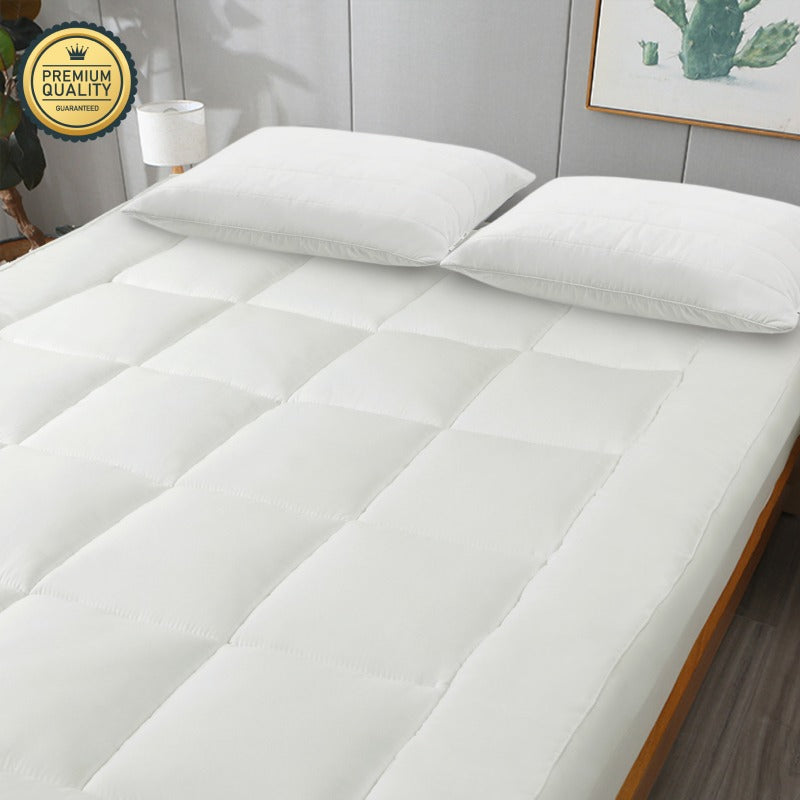 White mattress topper on a bed with pillows in a bedroom setting, featuring a 'Premium Quality' badge.