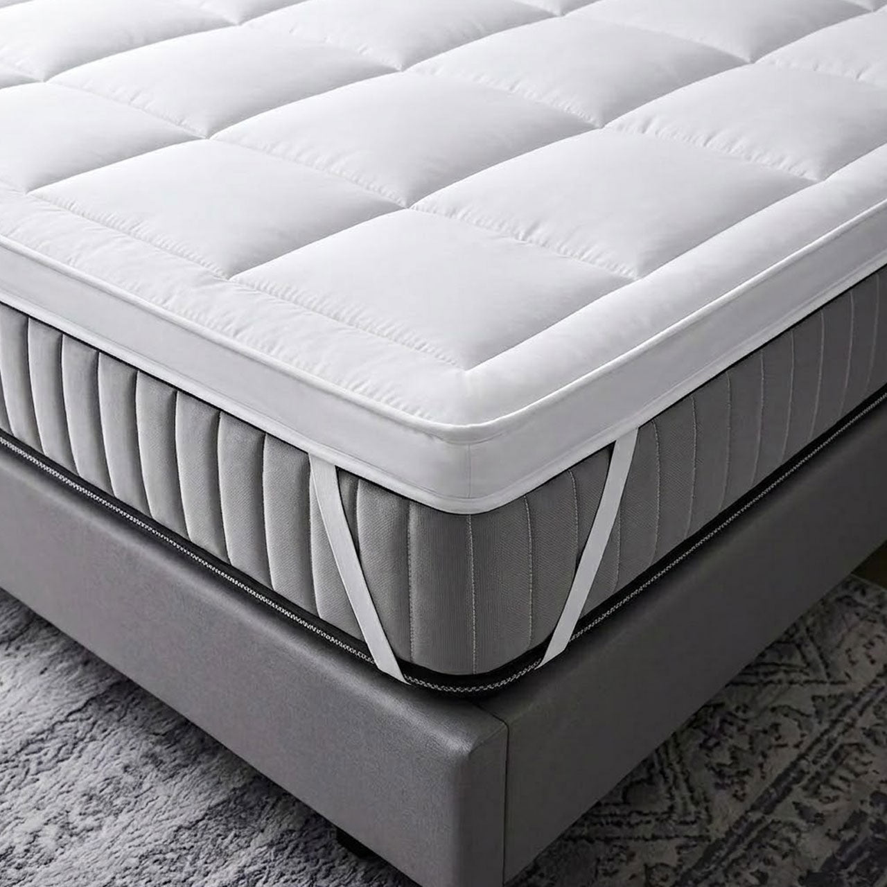 Gray mattress on a bed frame with a textured gray carpet in the background