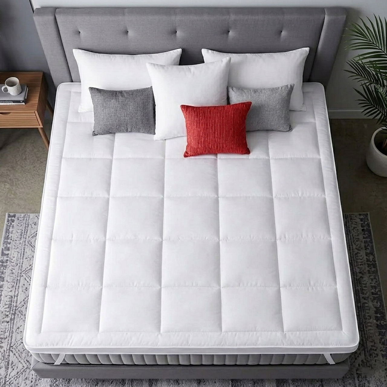 White mattress topper on a bed with decorative pillows in a bedroom setting.