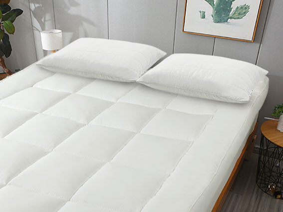 A hand is placed on a soft white bed